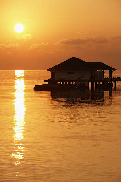 Sunset and a water bungalow in the Indian Ocean stock photo