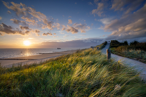 two people walking along the coastal path at sunset at the Zeeland coast near Zoutelande, North Sea