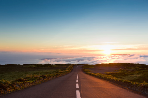 Highway through the beautiful nature down towards the atlantic ocean, leading into amazing cloudscape and sunset.