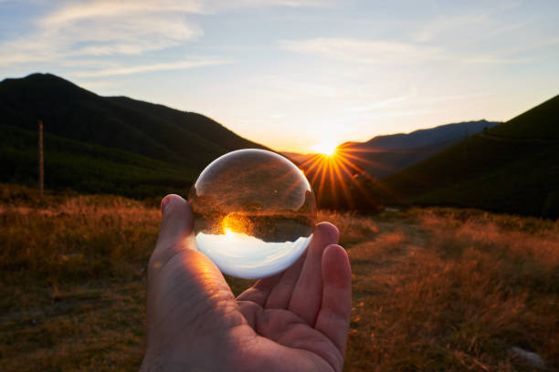 Sunset in the mountains of southern Asturias in Spain with one hand holding a crystal ball that flips everything stock photo