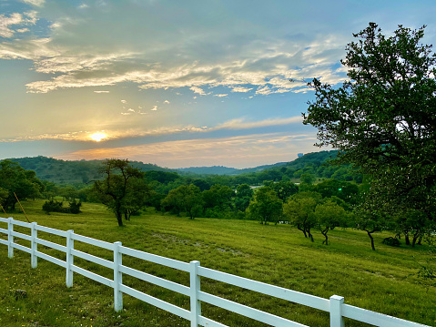 Sunsetting over the Texas hill country with a green tree covered field