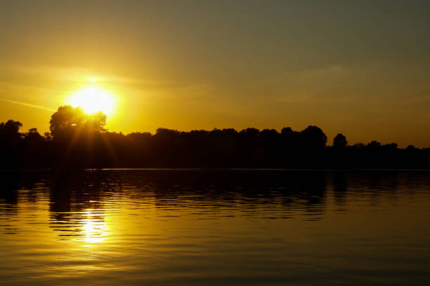 Sunset on a river landscape silhouette with reflection of the sun stock photo