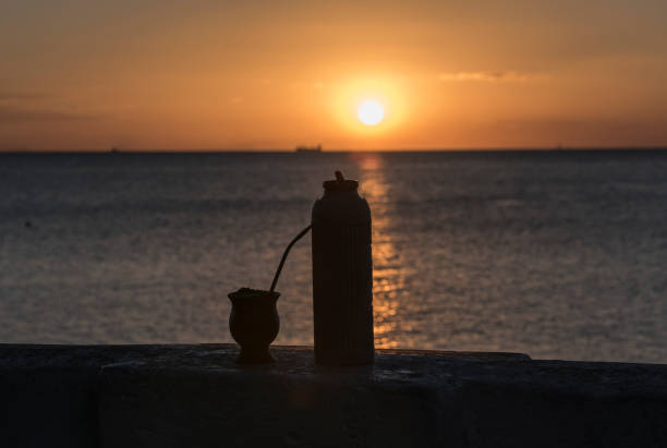 Sunset on the beach with silhouette of appliance for mate and gourd. stock photo