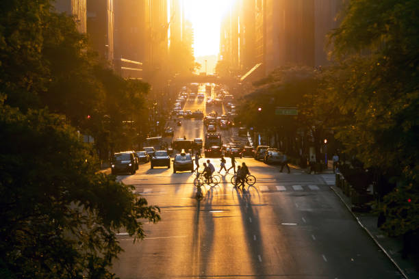 Sunset over 42nd Street casts long shadows from the people and cars in Midtown Manhattan, New York City stock photo