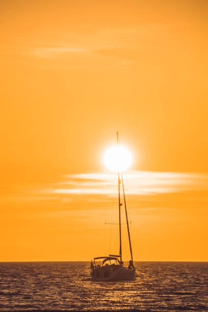 sunset Little white boat floating on the water towards the horizon in the rays of the setting sun michigan shooting stock pictures, royalty-free photos & images