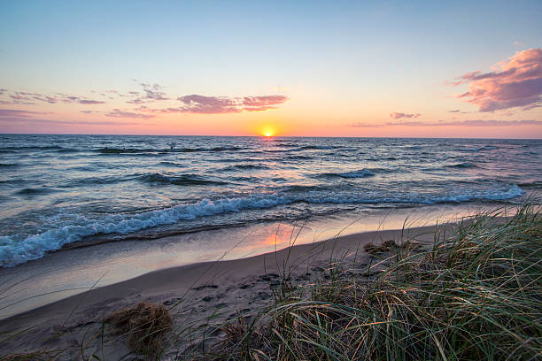 Sunset Seascape Beach Horizon The sunset over the beautiful shores of Lake Michigan with dune grass in the foreground and sunset reflections on the sandy beach. great lakes stock pictures, royalty-free photos & images