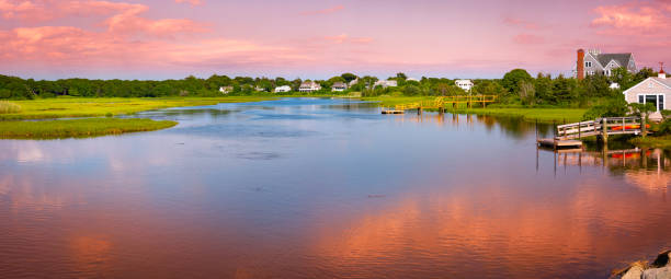 Sunset seascape with pink clouds and water reflections. Peaceful summer marsh river landscape over Bumps River near Craigville Beach on Cape Cod. stock photo
