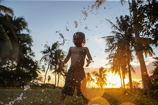 A small boy plays in an outdoor shower in the tropics