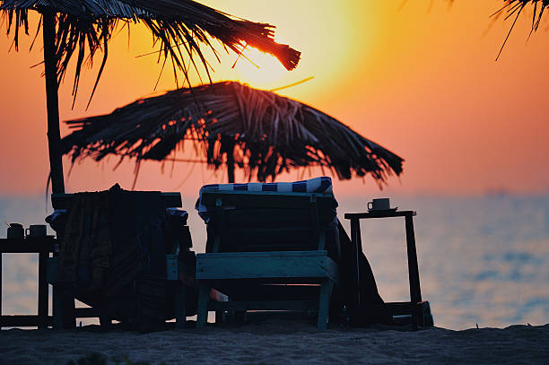 Sunset view from beach with palm leaves and chairs stock photo