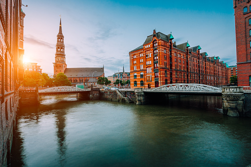 Sunset view on the old town with canals and metal arch bridges, Saint Catherine's church and Warehouse district in Hamburg city, Germany