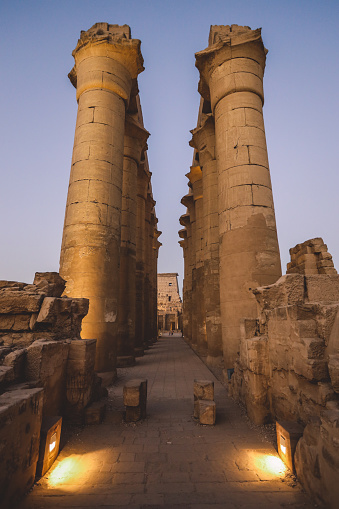 Sunset View to an Illuminated in Yellow Grand colonnade of large Ancient Egyptian temple in Luxor, Egypt