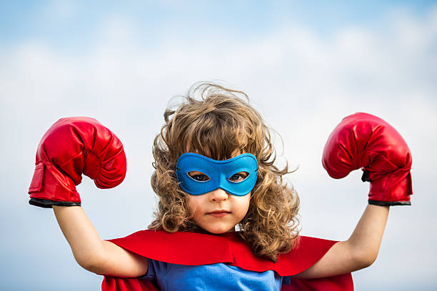 Superhero kid. Girl power concept Superhero kid wearing boxing gloves against blue sky background. Girl power and feminism concept costume photos stock pictures, royalty-free photos & images