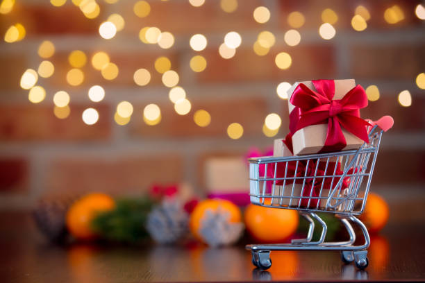 supermarket cart and gifts on background with fairy lights stock photo