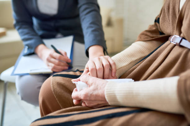 Supportive Female Psychologist Close up of female psychologist holding hand of senior woman during therapy session, copy space grief stock pictures, royalty-free photos & images