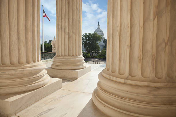 Supreme Court columns with American flag and US Capitol Close up of the columns  of the Supreme Court building with an American flag and the US Capitol in the background architectural column photos stock pictures, royalty-free photos & images