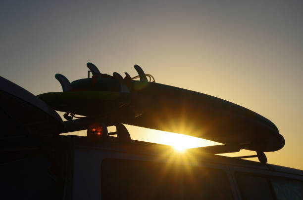 Surfboards on the roof of a van. Surf and travel concept. Sunset in the background. stock photo