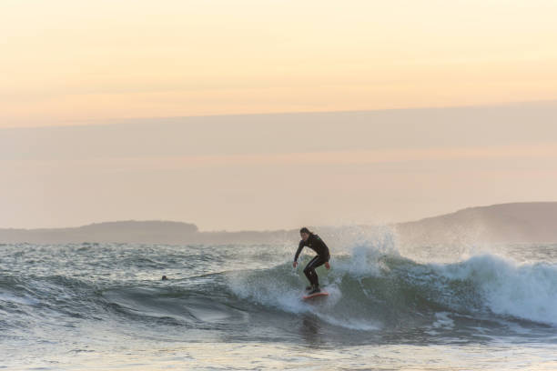 Surfer enjoying evening surf in rough sea at dusk. stock photo