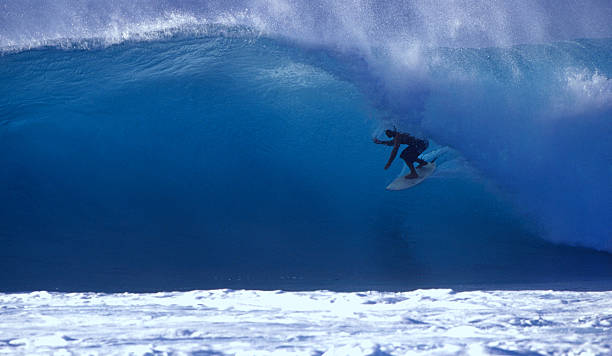 surfer on a blue wave surfer on a backlit blue wave, getting barrelled at rocky point, on hawaii's north shore big wave surfing stock pictures, royalty-free photos & images