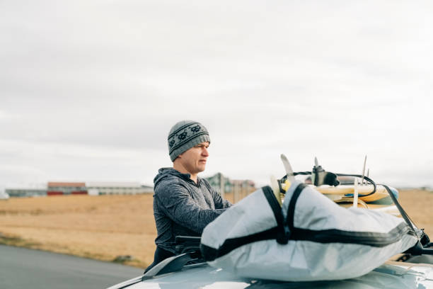 surfer packen surfbrett auf auto dachträger - auto packen für den urlaub winter stock-fotos und bilder