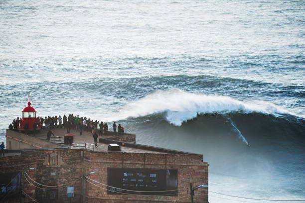 surfista cavalca una grande onda di 15 metri a nazare, in portogallo. - nazaré foto e immagini stock