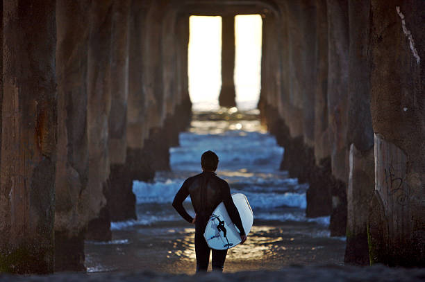 Surfer Standing Under the Pier stock photo