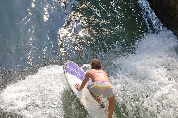Surfers in the Isar canal in Munich Surfers at a small waterfall in the Isar Canal on a summer day river isar stock pictures, royalty-free photos & images
