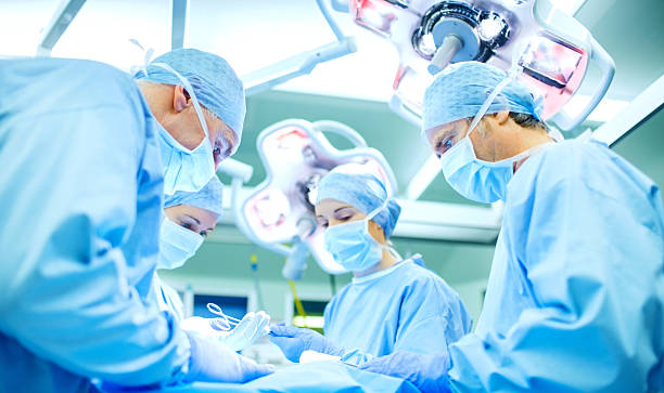 Surgeons Performing Surgery On Patient In Operating Room stock photo