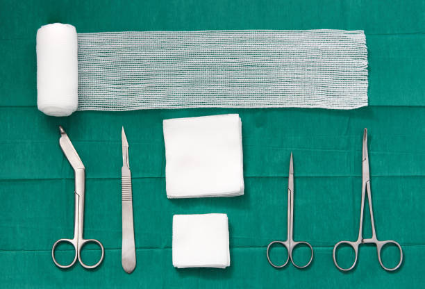 surgery tools ,scissors ,roll gauze,bandage,pad,cramp,blade,knife on green surgical dress background ,bird eye view stock photo