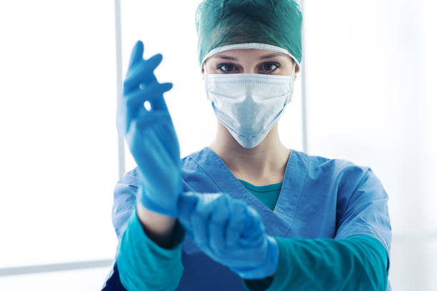 Surgical preparation Female surgeon preparing for the surgical operation, she is wearing gloves and looking at camera, healthcare and preparation concept surgeon stock pictures, royalty-free photos & images