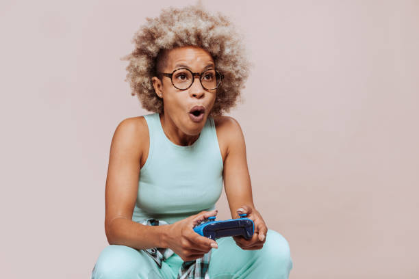 Surprised afro latin american woman playing video game with controller stock photo