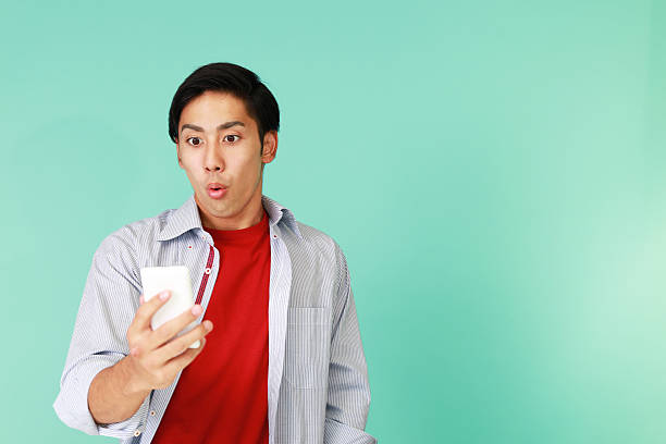 Surprised Asian man Man holding a smart phone smart phone green background stock pictures, royalty-free photos & images