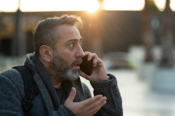 Surprised businessman talking on the phone at street after work stock photo