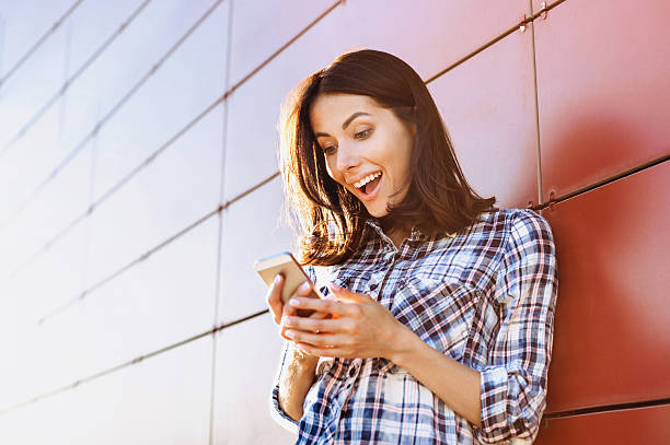 Surprised girl using smart phone Happy young woman using smart phone good news stock pictures, royalty-free photos & images