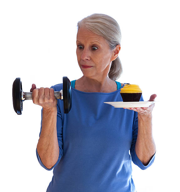 Surprised Woman Holding Dumbbell and Cupcake stock photo