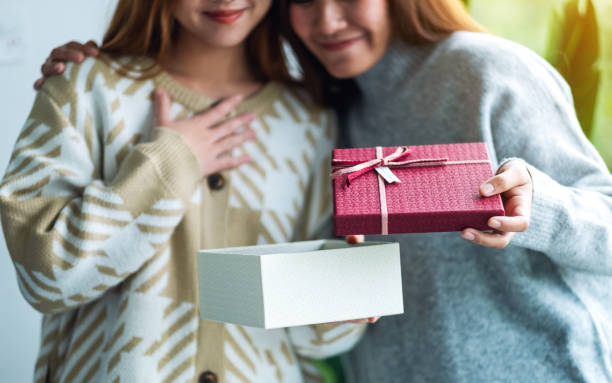 verraste jonge vrouwen die samen een giftdoos openen - unbox stockfoto's en -beelden