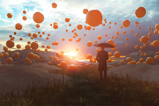 Surreal image of man standing in the field with falling spheres - this is entirely 3D generated image.