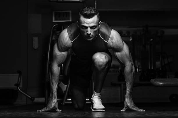 Survival Of The Fittest Strong Muscular Men Kneeling On The Floor - Almost Like Sprinter Starting Position male bodybuilders stock pictures, royalty-free photos & images