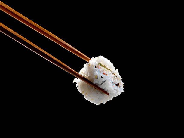 Sushi in Chopsticks  chopsticks stock pictures, royalty-free photos & images
