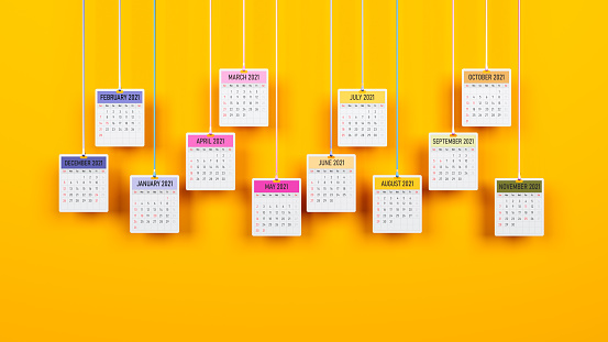Suspended monthly calendar pages on yellow-colored background Horizontal composition with copy space