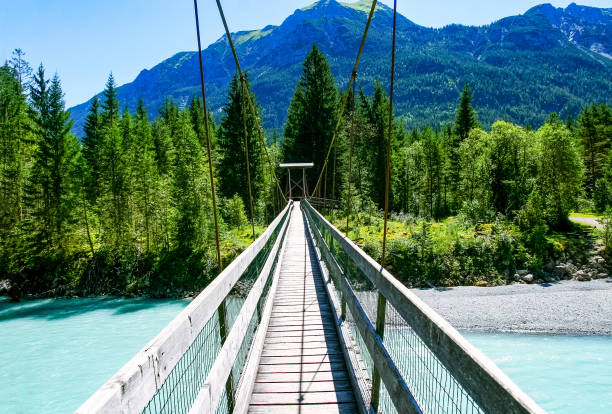 Suspension Bridge near Forchach, Lechtaler Alps, Tyrol, Austria A long footbridge across a pretty stretch of the river Lech, Tyrol, Austria lech river stock pictures, royalty-free photos & images