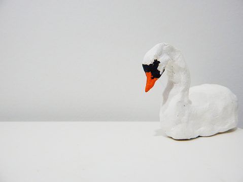 Swan molded from clay positioned at side of a table