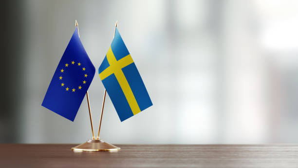 Swedish And European Union Flag Pair On A Desk Over Defocused Background Swedish and European Union flag pair on desk over defocused background. Horizontal composition with copy space and selective focus. swedish flag photos stock pictures, royalty-free photos & images