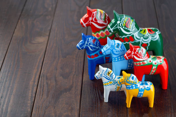 Swedish traditional souvenir wooden dala horses, hand craft made and painted, different colors and sizes, on wooden background,  horizontal, copy space stock photo