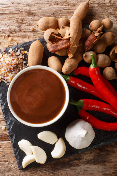 Sweet and sour spicy tamarind sauce with ingredients close-up on a table. Vertical top view Sweet and sour spicy tamarind sauce with ingredients close-up on a wooden table. Vertical top view from above chutney stock pictures, royalty-free photos & images