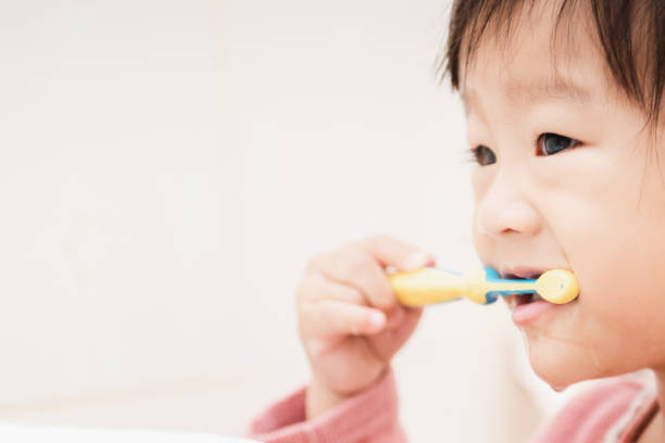 アジアのかわいい子供の浴室で彼女の歯を磨く女の子 ストックフォト