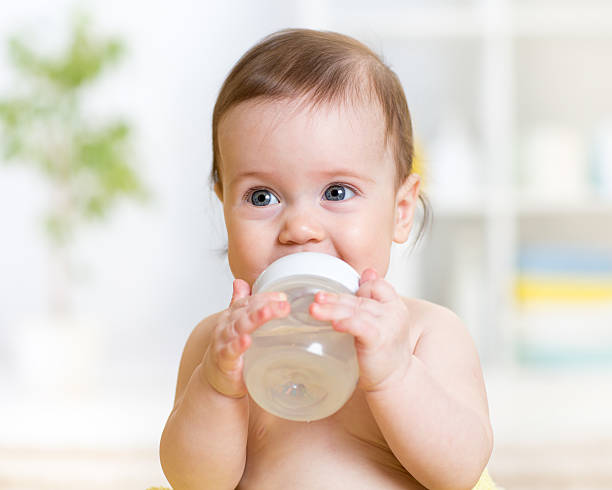 sweet baby holding bottle and drinking water stock photo