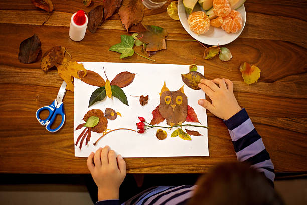 Sweet child, boy, applying leaves using glue while doing arts stock photo