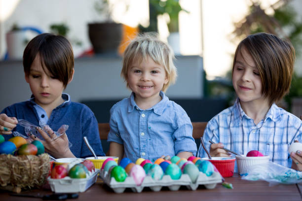 Sweet children, brothers, coloring and painting eggs for Easter in garden, outdoor at home in backyard  easter sunday stock pictures, royalty-free photos & images