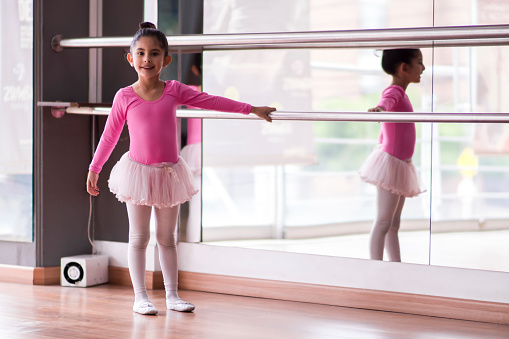 Sweet little ballerina holding on to rail during class smiling at camera - Lifestyles