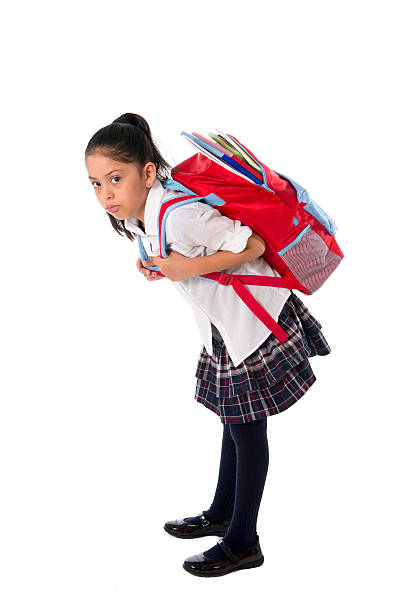 sweet little girl carrying very heavy backpack or schoolbag full stock photo